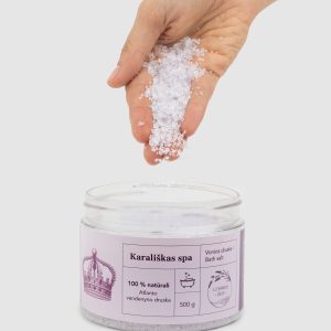 Ranka beria vonios druskos „Karališkas SPA“ kristalus į atidarytą indelį