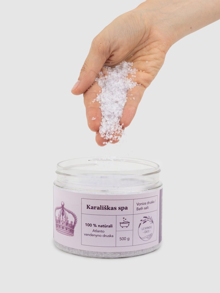 Ranka beria vonios druskos „Karališkas SPA“ kristalus į atidarytą indelį
