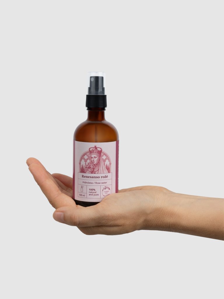 A bottle of “Renaissance Rose” rose hydrosol with a spray pump on an open palm