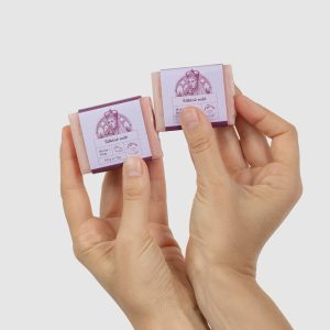 Two hands hold two small 50 g pieces of “Silky Rose” soap bar