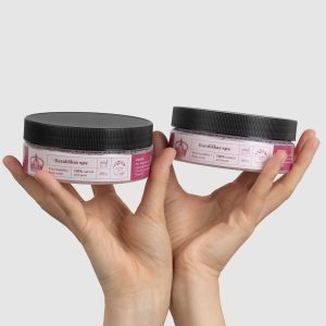 Two jars of “Royal SPA” rose body scrub with black lids in hands