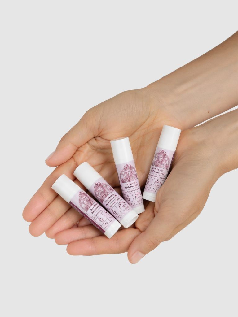 Four “Queen Barbara's Rose” lip balms placed in cupped hands
