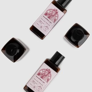 Two bottles of “Royal SPA” rose body wash and caps laid out, top view