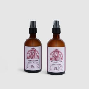 Two brown bottles of “Renaissance Rose” rose hydrosol with sprays on a light background