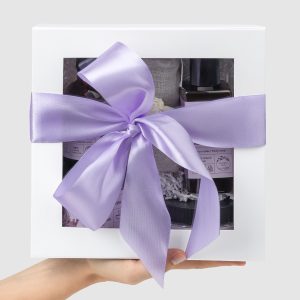 Closed white “Royal SPA” gift box with a purple ribbon held in hands