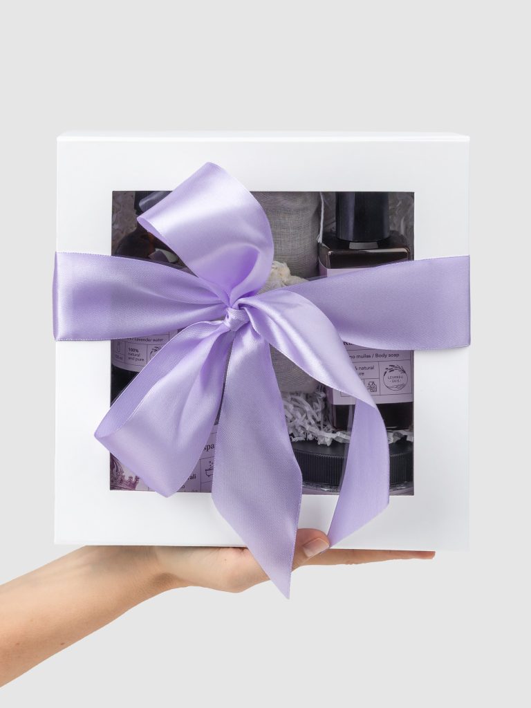 Closed white “Royal SPA” gift box with a purple ribbon held in hands