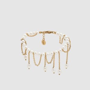 Gold-coloured bracelet “The Queen's Whim” with pearls and dangling chains on a light background