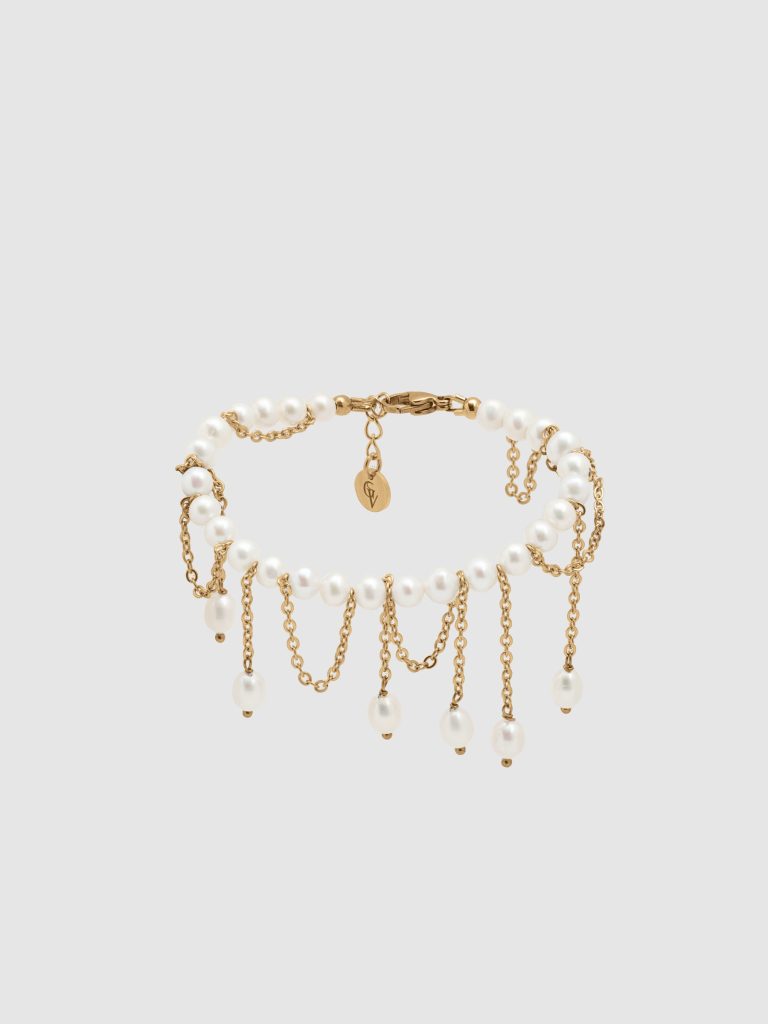 Gold-coloured bracelet “The Queen's Whim” with pearls and dangling chains on a light background