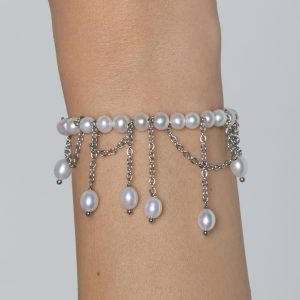 Silver-coloured “The Queen's Whim” pearl bracelet with dangling chains on a wrist