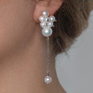 Close-up of the earring “The Queen's Garden” with a cluster of pearls and a hanging pearl on a model's ear