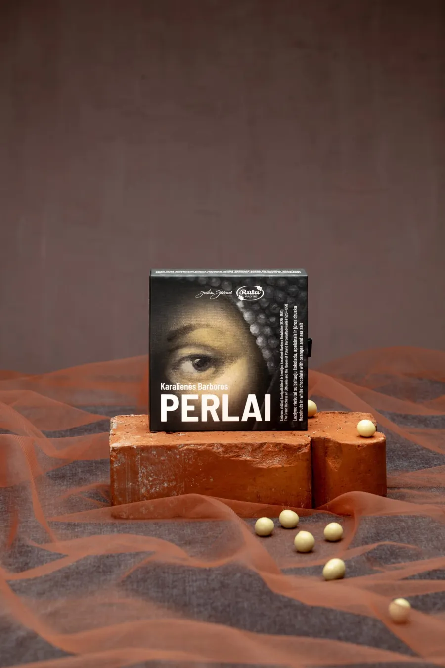 Juodojo šokolado plytelė „Perlai“ iš rinkinio „Karališko dvaro istorijos“ ant plytos su perlais