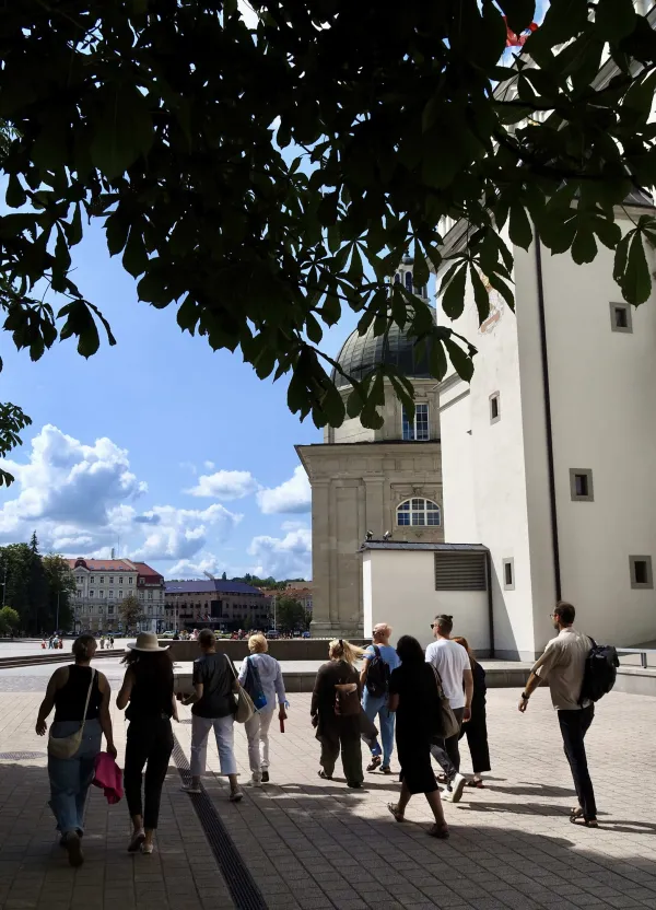 Tour group walking towards the Palace of the Grand Dukes of Lithuania past tree branches – “Royal Vilnius Love Stories”