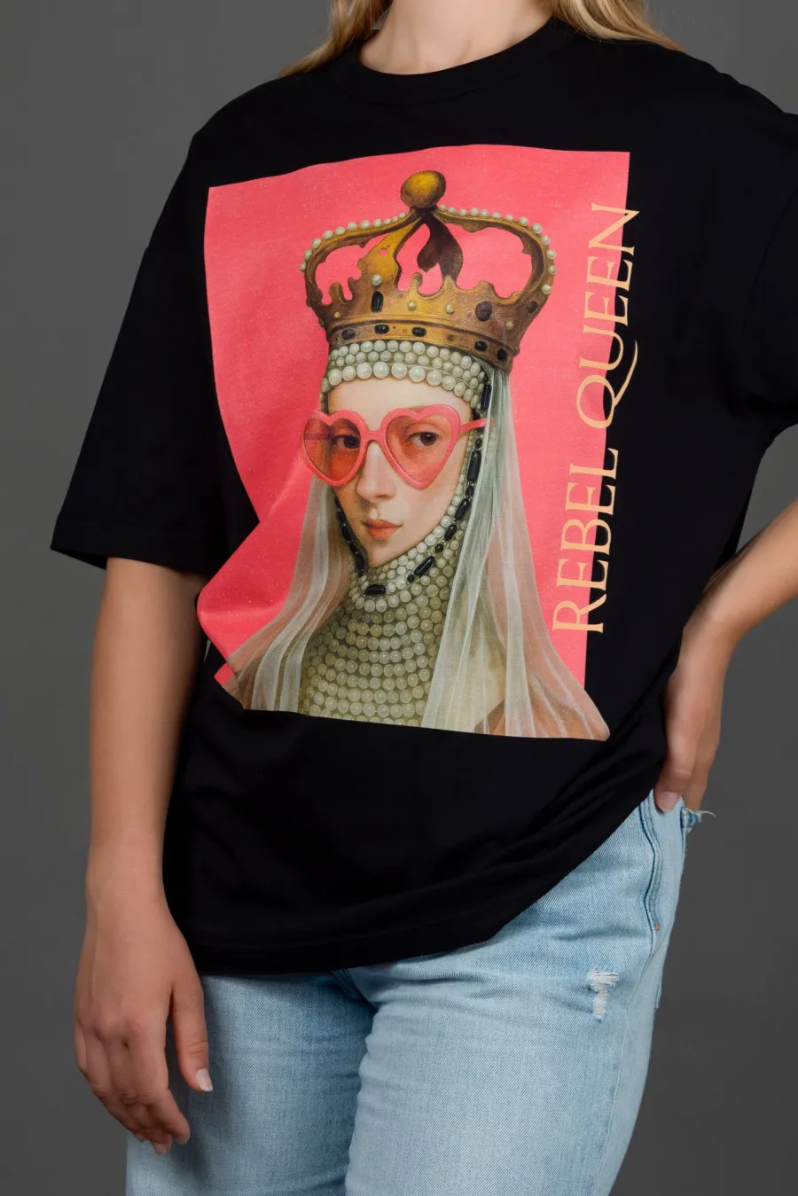 Woman wearing a black “REBEL QUEEN” T-shirt with a portrait of a queen in pink glasses