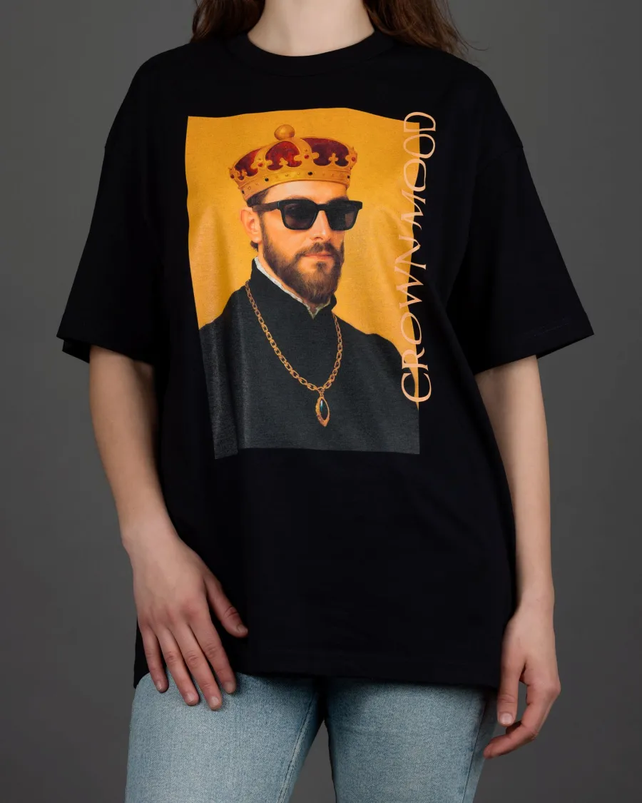 Woman in a black “CROWN MOOD” T-shirt and light jeans, front view