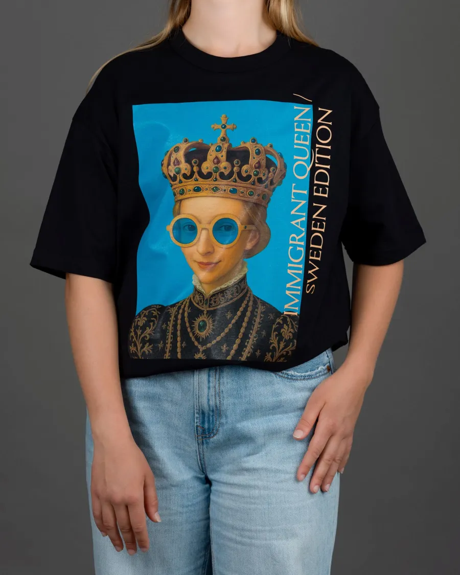 Woman in a black “IMIGRANT QUEEN / SWEDEN EDITION” T-shirt and jeans, hand on hip