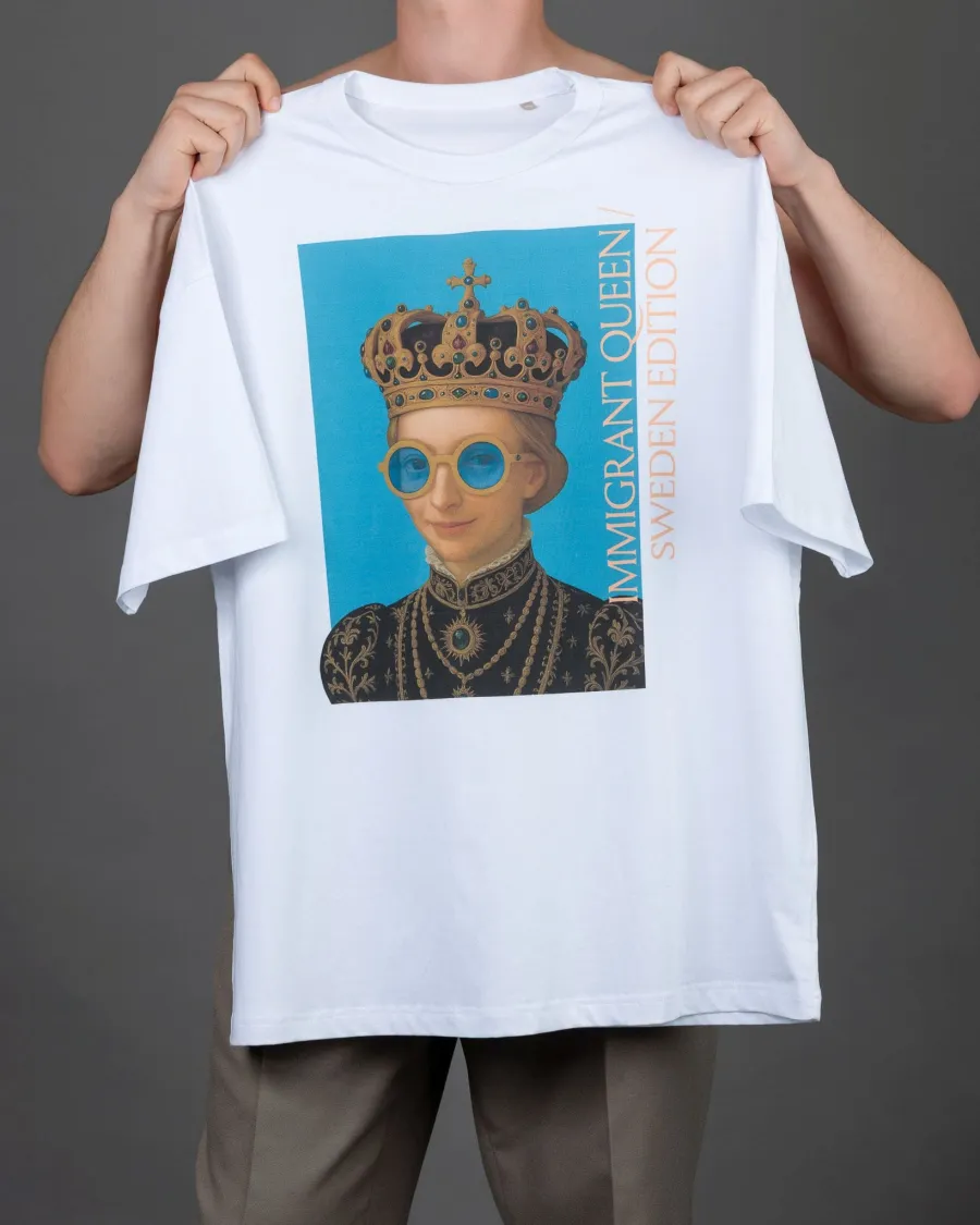 Man holding up a white “IMIGRANT QUEEN / SWEDEN EDITION” T-shirt in front of him