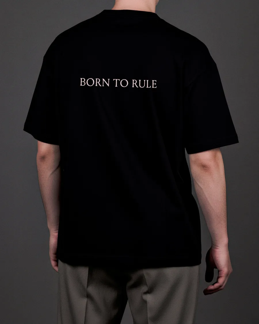 Back of the black “KARŪNA” T-shirt with the words “Born to rule” on a man