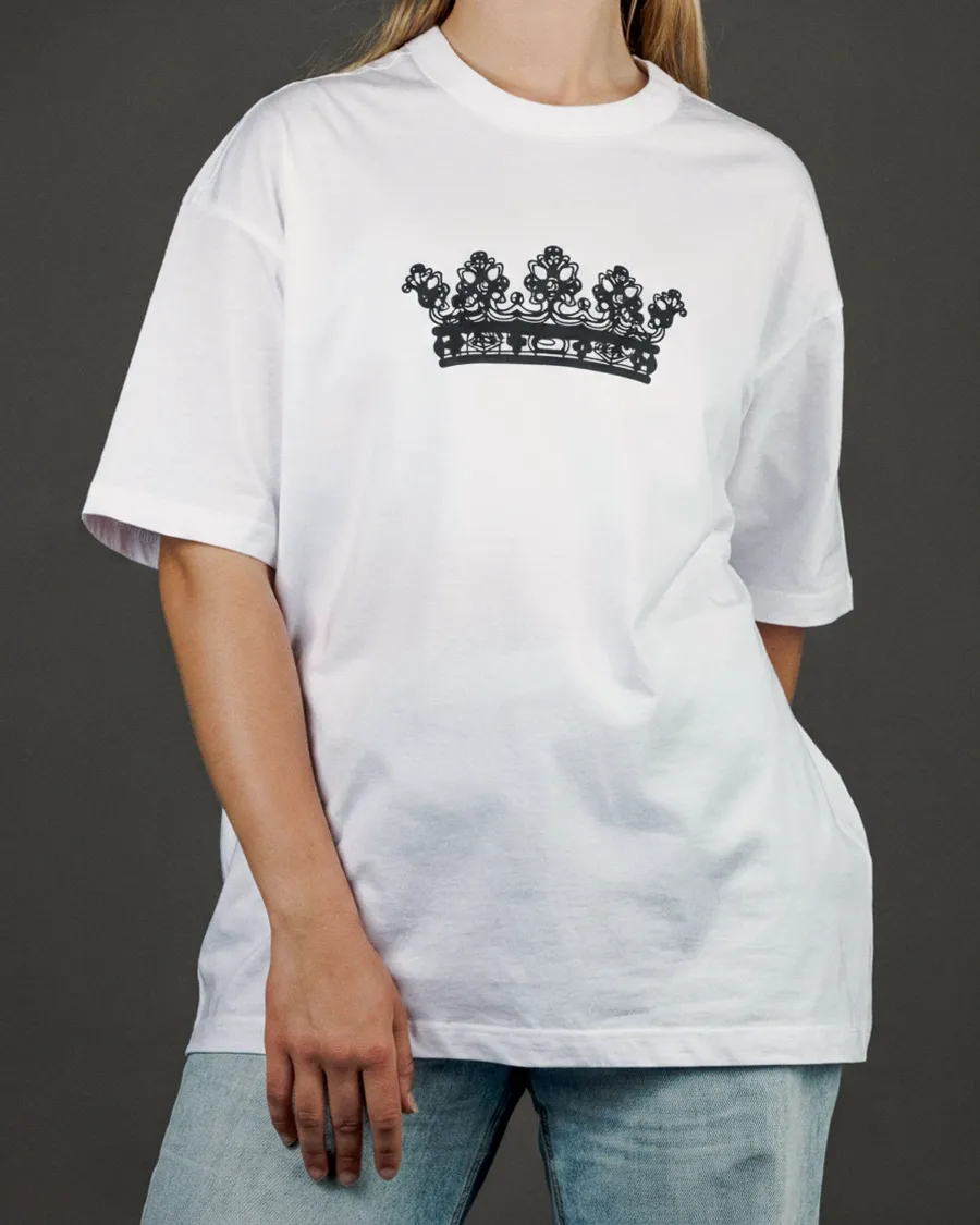 Woman wearing a white “KARŪNA” T-shirt with a crown drawing and jeans