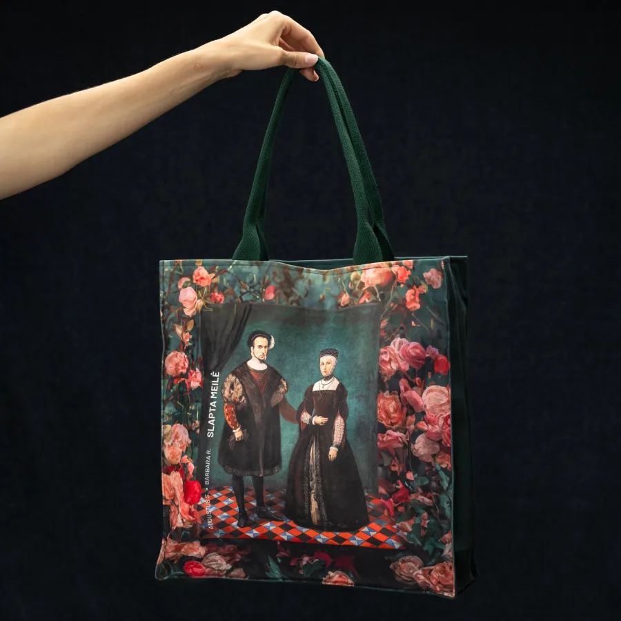 “Slapta meilė” handbag with a portrait of a couple surrounded by roses and green handles, held in a hand