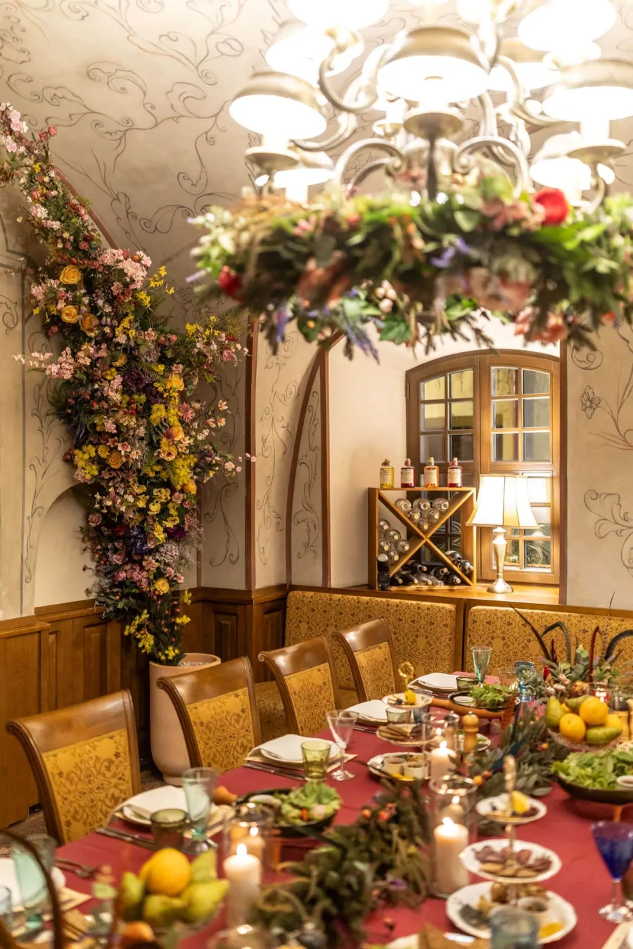 Hall decorated with flowers, with a laid table and a chandelier – Vilnius Royal Hunt Dinner