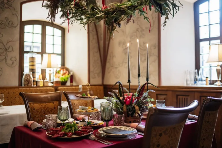 The hall of the “Lokys” restaurant with a laid table, tall candles and a flower arrangement