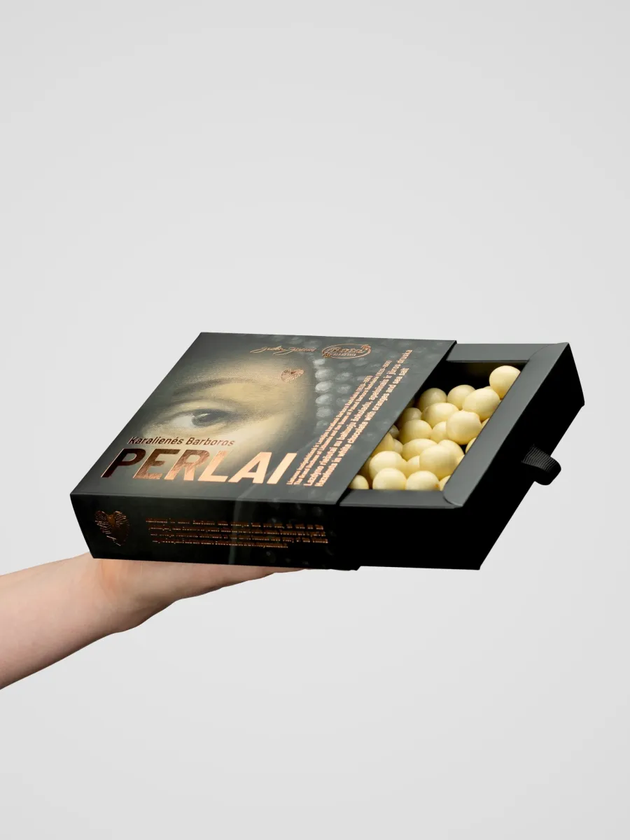 Pull-out box of “Queen Barbara's Pearls” with white sweets held in a hand