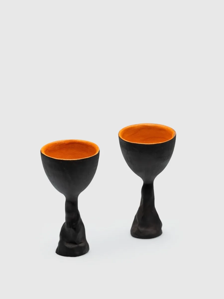 Two black Kings' Goblets with orange insides on a light background, front view