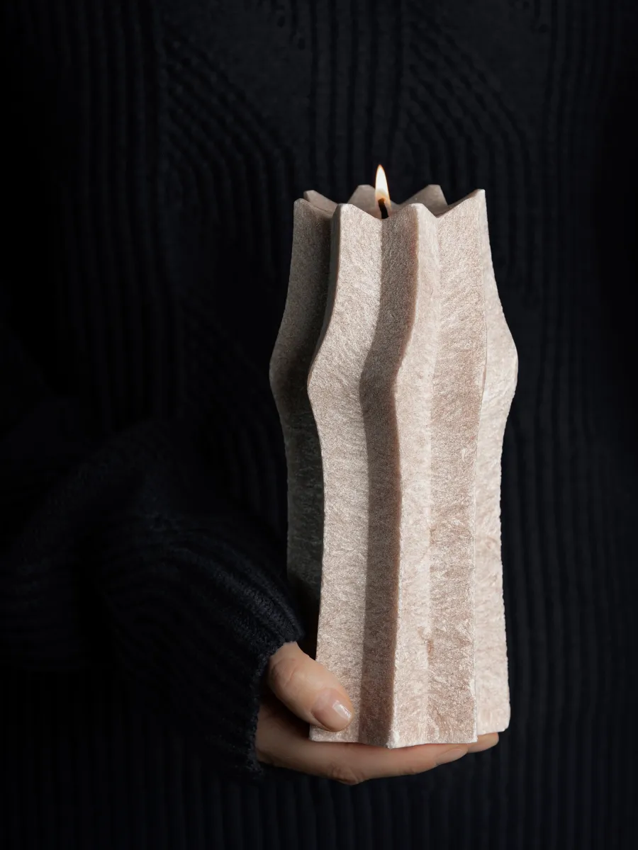 Powder-coloured “King Sigismund Augustus” candle in hands on a dark background