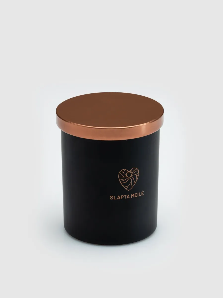 Closed “Slapta meilė” candle in a black jar with a copper-coloured lid on a light background