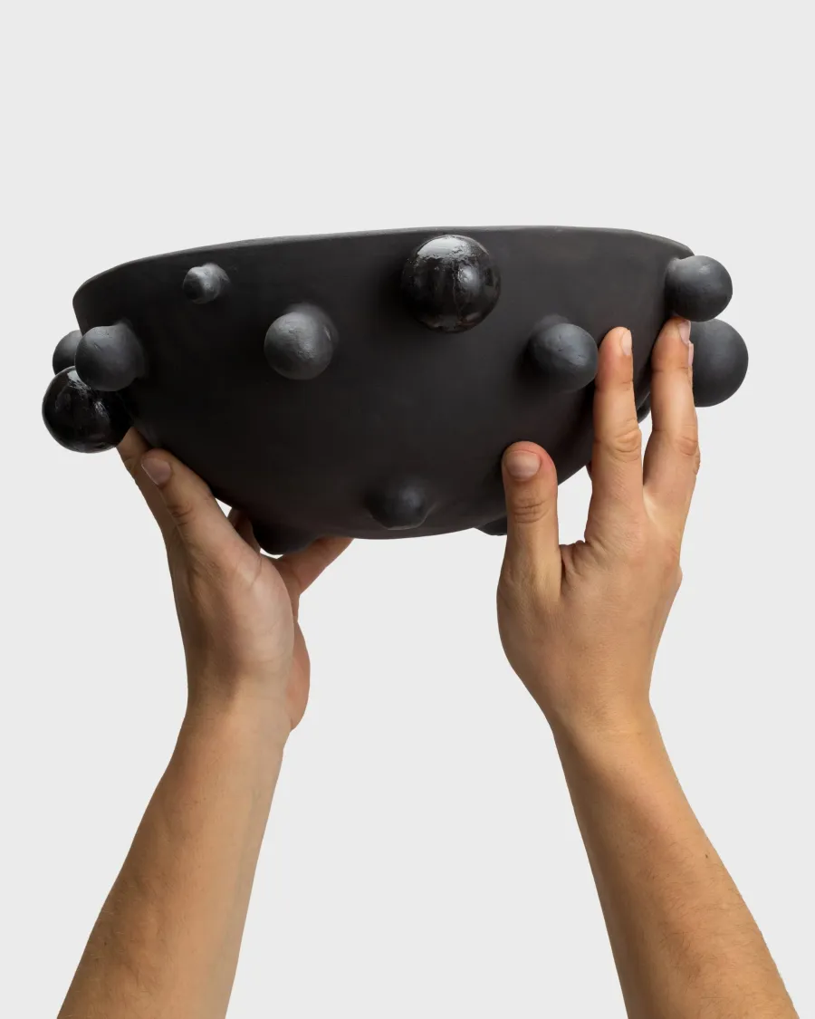 Large matte black “The Queen's Pearl Bowl” held in hands, side view
