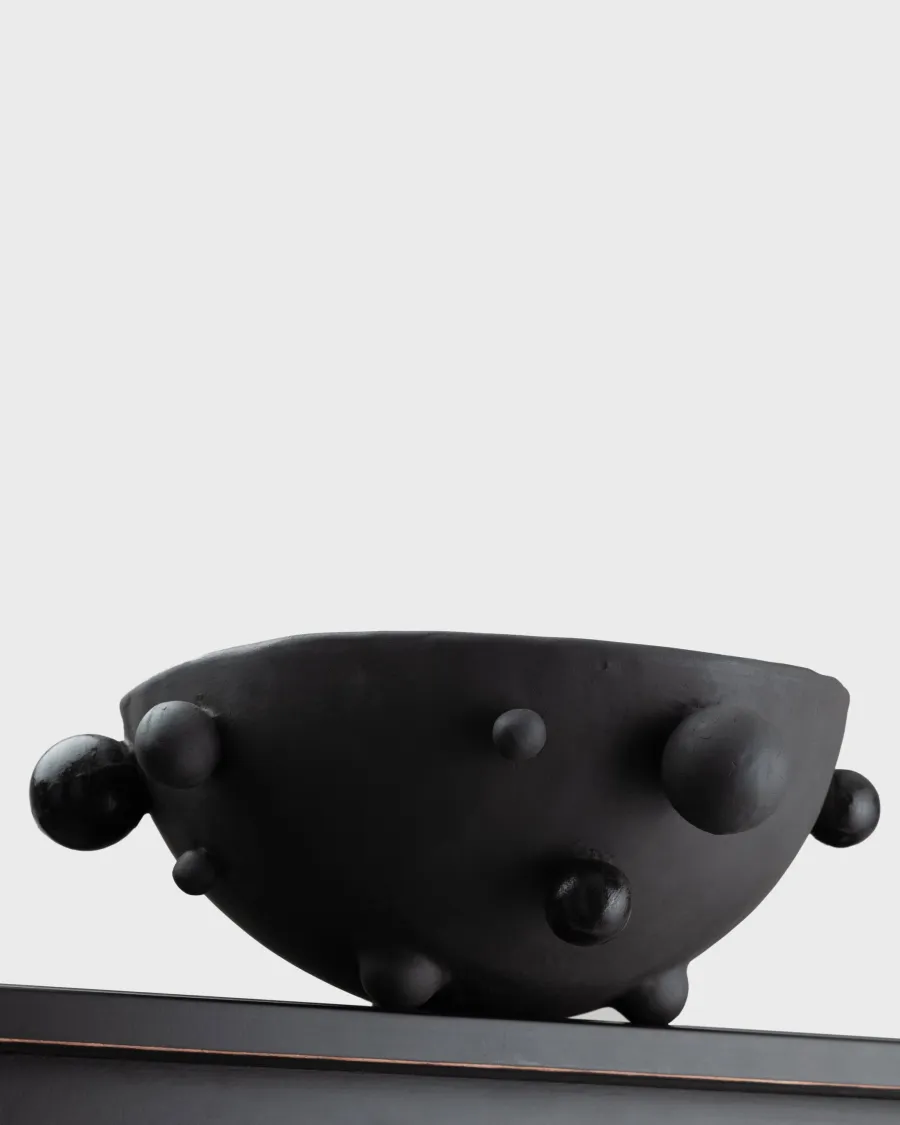 Side of a medium matte black “The Queen's Pearl Bowl” on the edge of a shelf