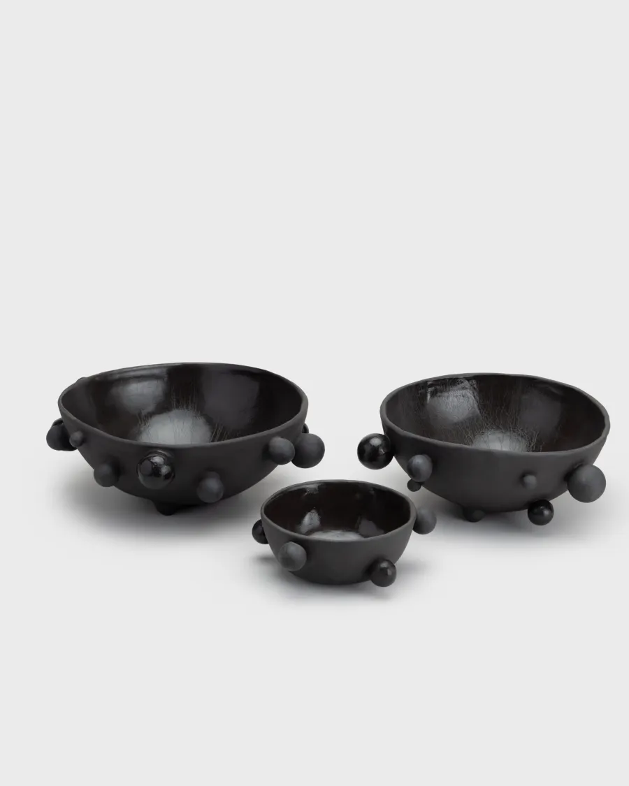 Three matte black “The Queen's Pearl Bowl” bowls in different sizes, angled view from above