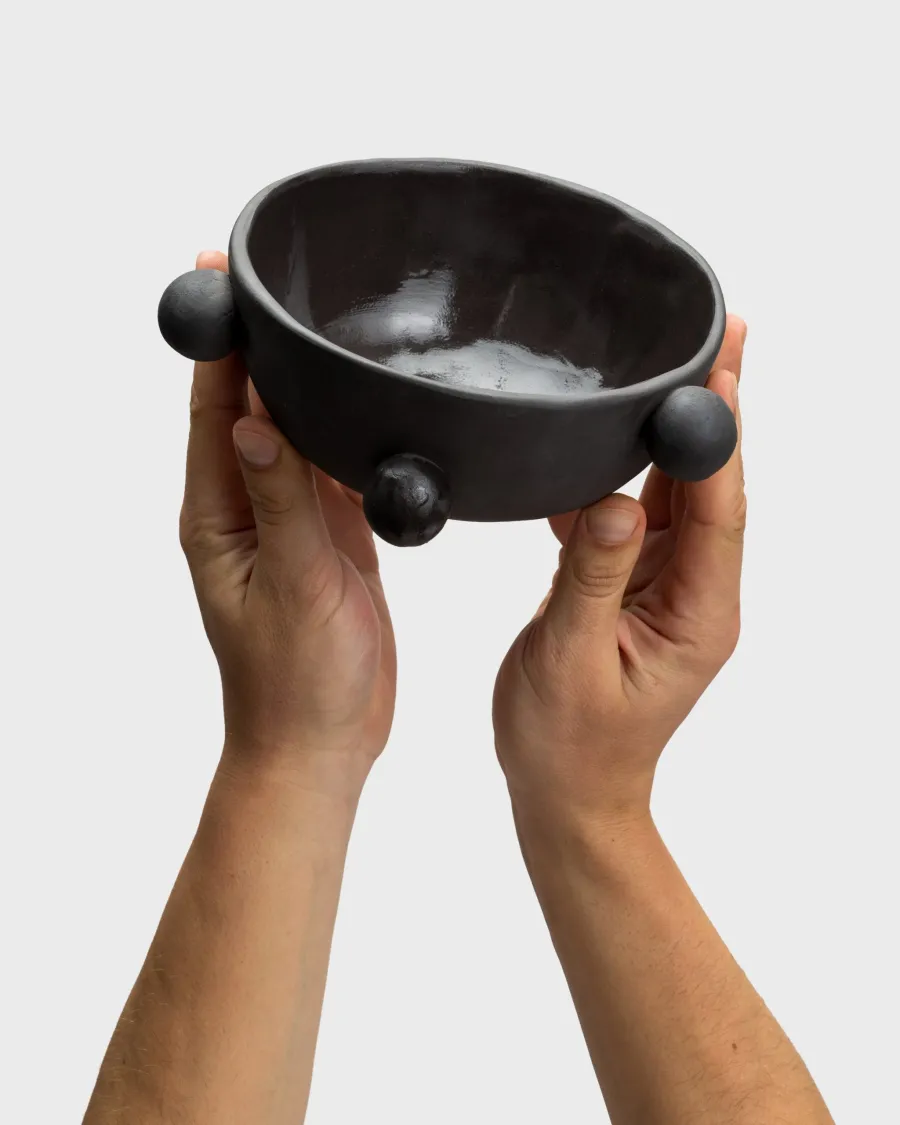 Small matte black “The Queen's Pearl Bowl” in two raised hands