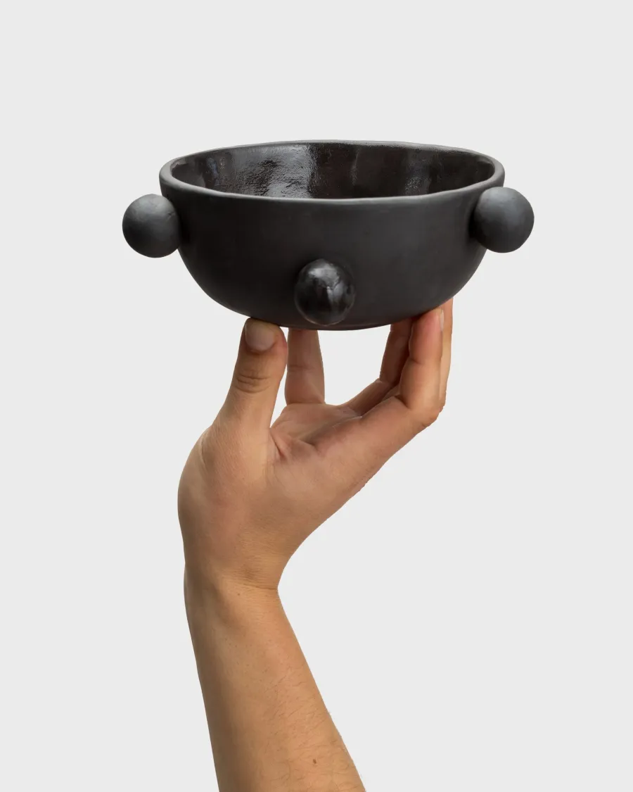 Small matte black “The Queen's Pearl Bowl” on the palm of one hand