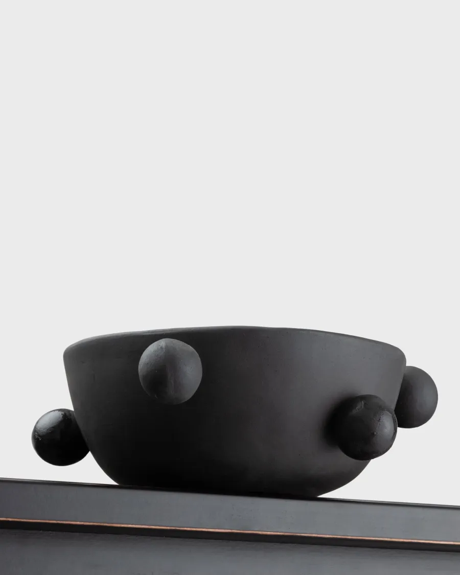Side of the small matte black “The Queen's Pearl Bowl” with balls on a shelf