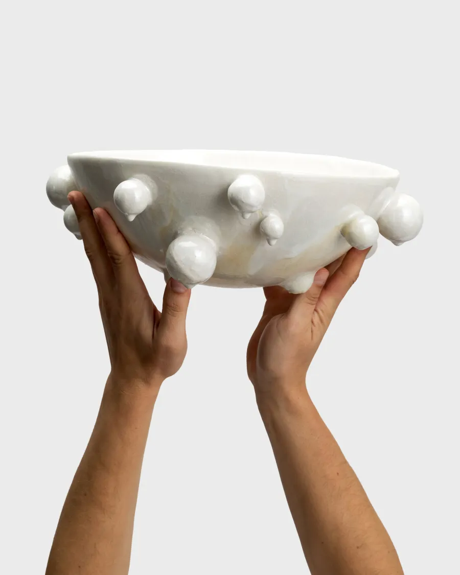 Large pearl white “The Queen's Pearl Bowl” raised in two hands, side view
