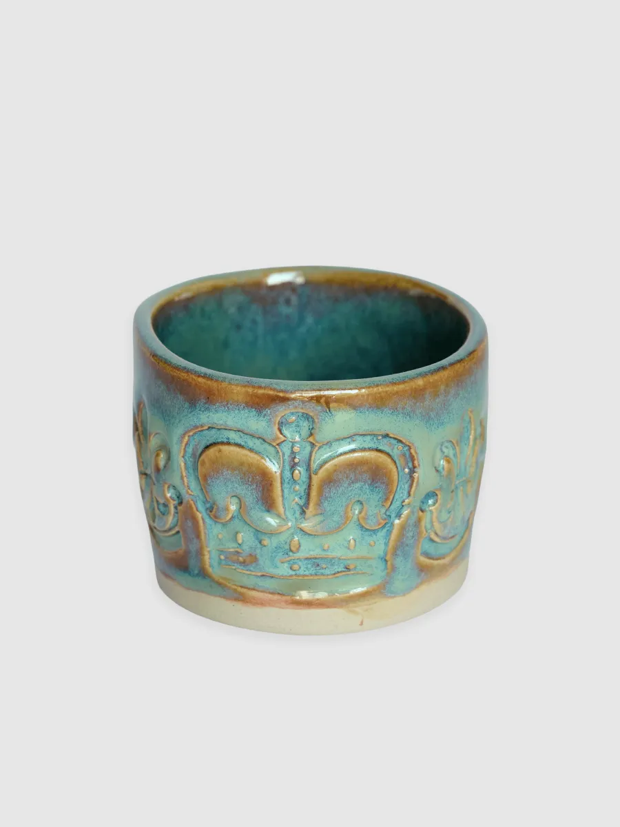 Turquoise “Throne” espresso cup with a relief crown on a light background