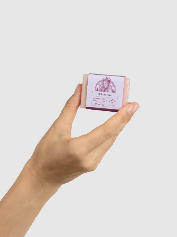 Ranka laiko mažą rausvą kieto muilo „Šilkinė rožė“ 50 g gabalėlį