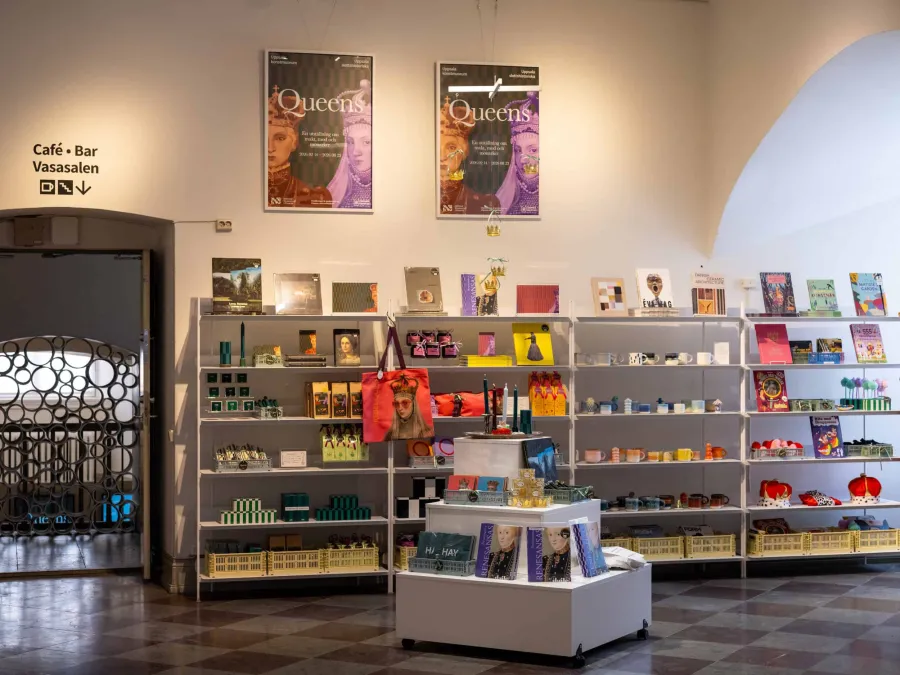 Museum shop with “Queens” posters, shelves of souvenirs and “Renaissance” magazines
