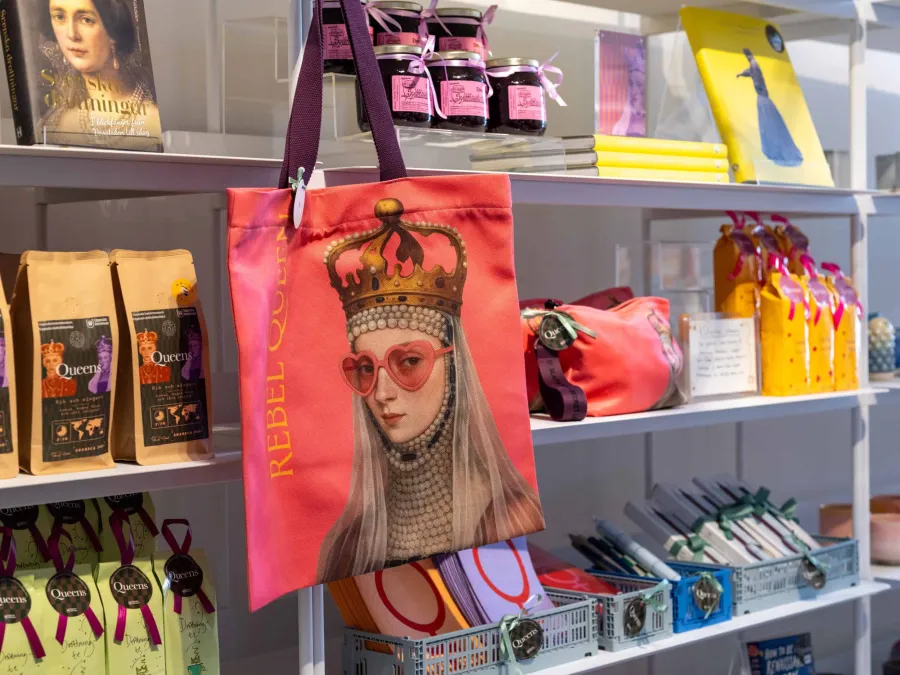 Shop shelf with a pink “Rebel Queen” bag, coffee, jams and souvenirs