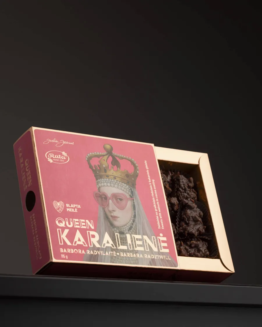 Open pink chocolate box “Queen Karalienė” with a portrait of the queen on a dark shelf