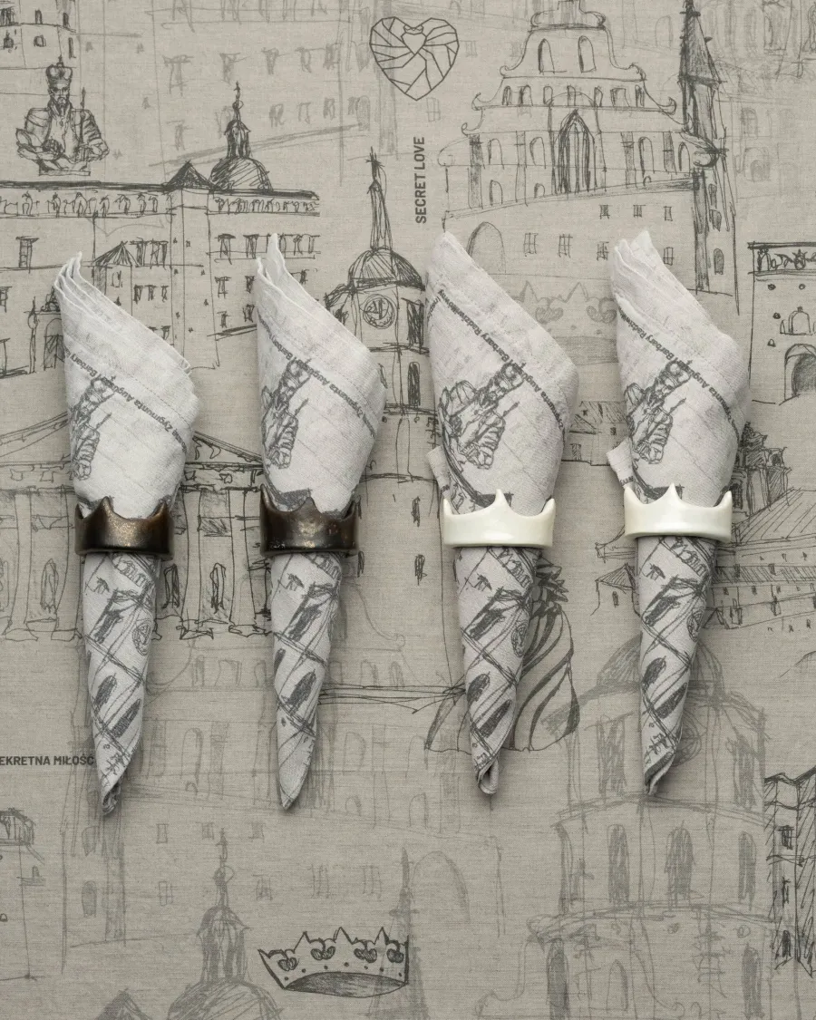 Four napkins with drawings of Vilnius in crown-shaped rings on a tablecloth with city views