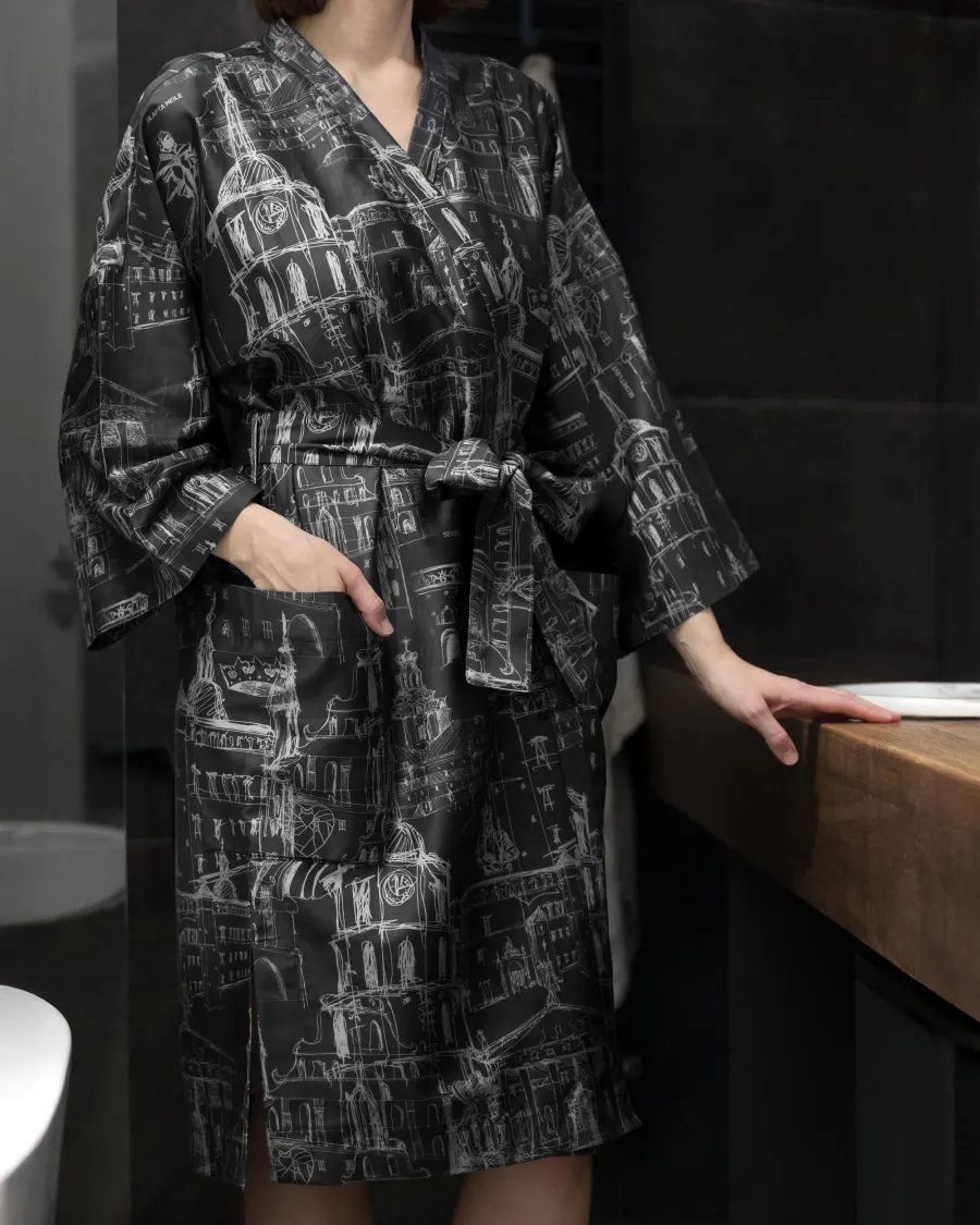 Woman in a robe with black and white drawings of Vilnius Old Town standing by a wooden table