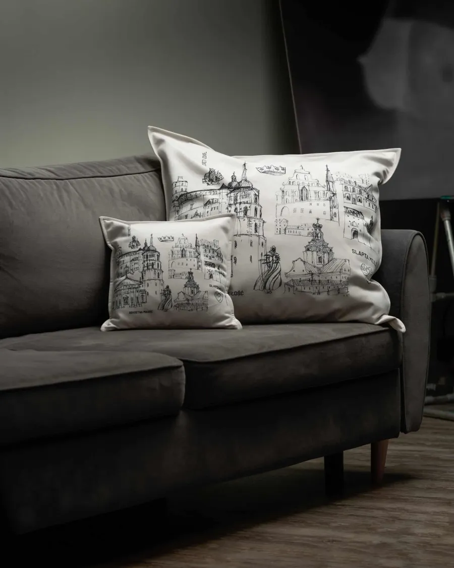 Two cushions with drawings of Vilnius Old Town on a dark velvet sofa