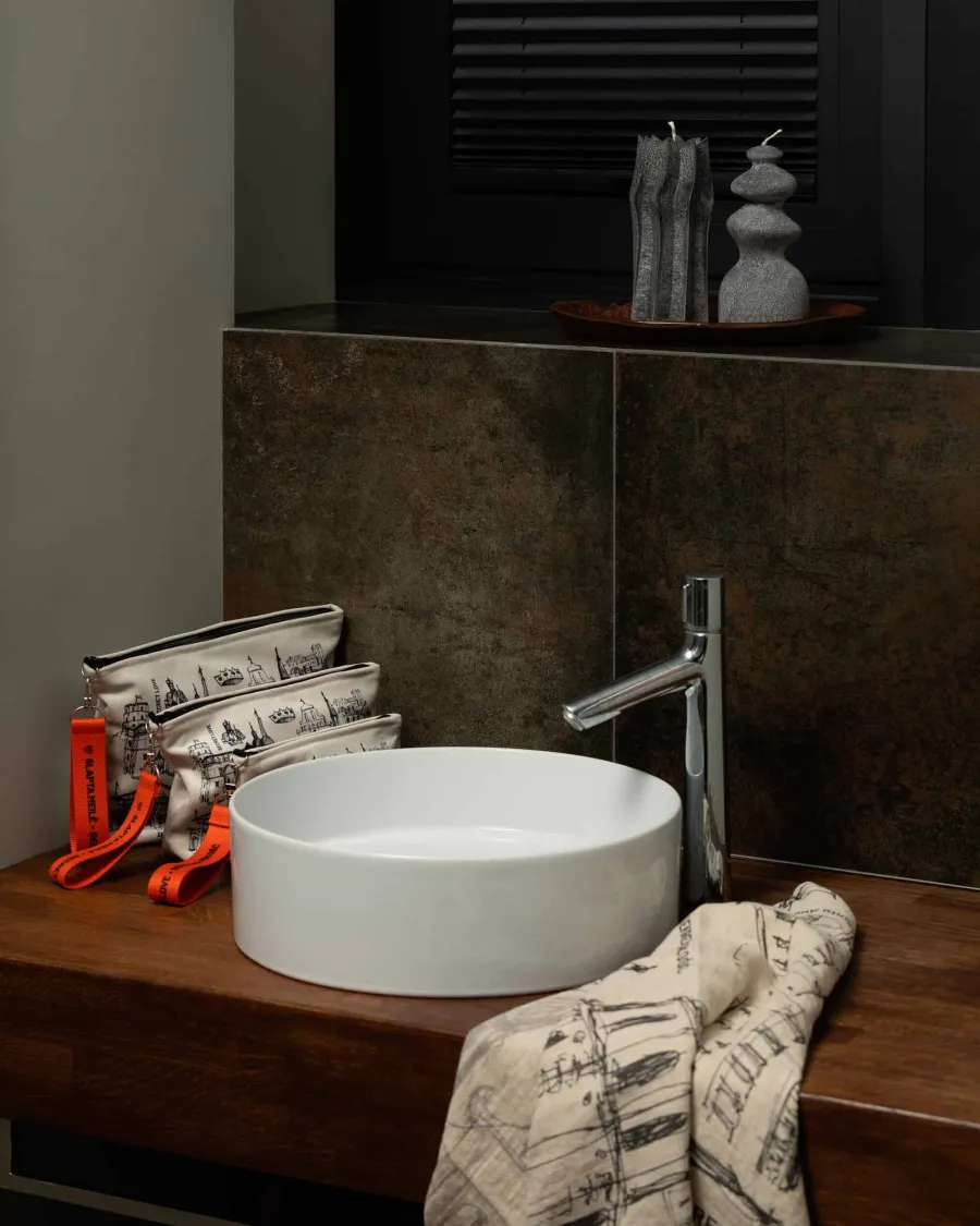 Cosmetic bags and a towel with Vilnius drawings on a wooden worktop by a washbasin