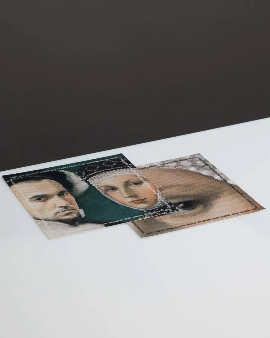 Two postcards with a portrait of a Renaissance man and a detail of a woman's eye on a white table