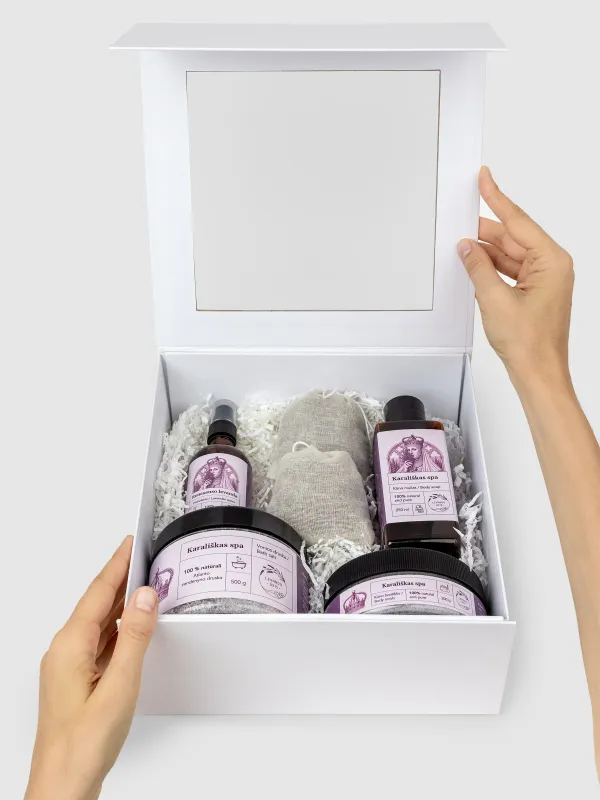 Atidaryta balta dovanų dėžė „Karališkas SPA“ su levandų produktais, laikoma rankomis